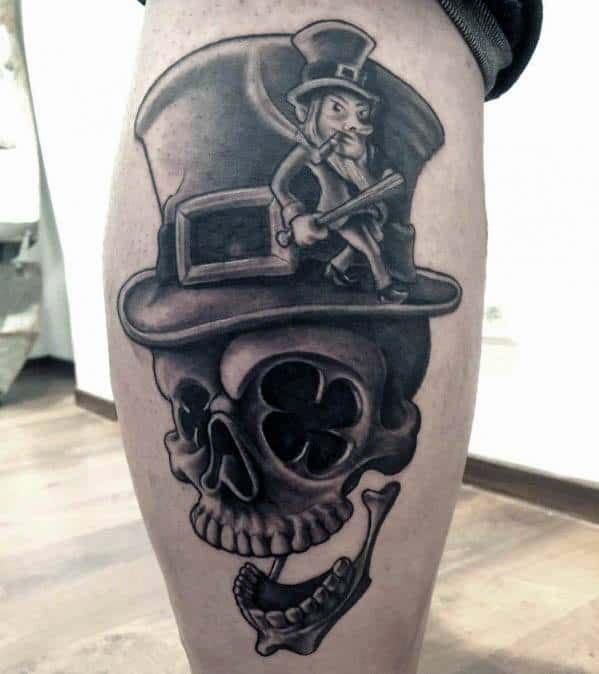 Black and grey tattoo of a skull wearing a top hat with a shamrock eye socket, featuring a small leprechaun sitting on the hat holding a shotgun.