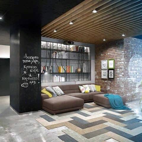 Modern living room with brown sectional, exposed brick, and geometric patterned flooring.