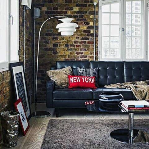 New York loft apartment with black leather sofa, exposed brick wall, and city-themed decor.