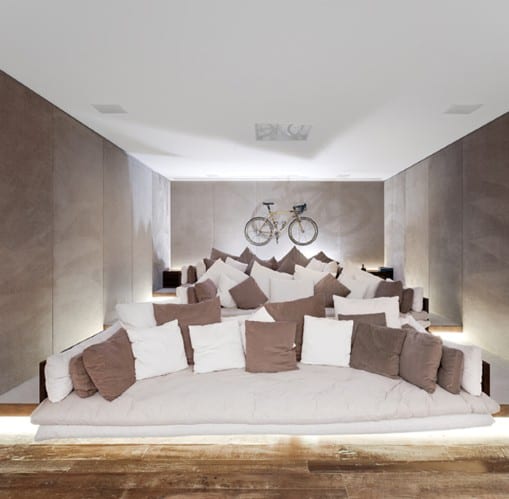 Modern room with tiered seating, numerous cushions, and a bicycle mounted on the back wall