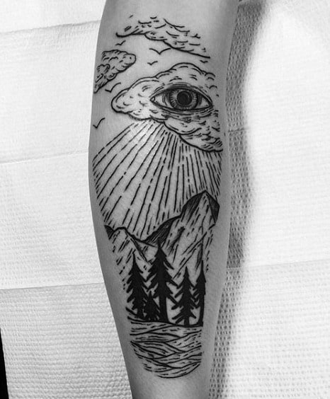 Black ink calf tattoo of a surreal mountain landscape with an all-seeing eye in the clouds, emitting sun rays over trees and a river