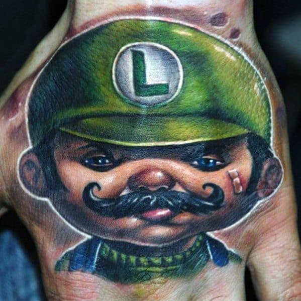Realistic tattoo of Luigi with a rugged, lifelike appearance, featuring a thick mustache, intense eyes, and a worn green cap, inked on the hand.