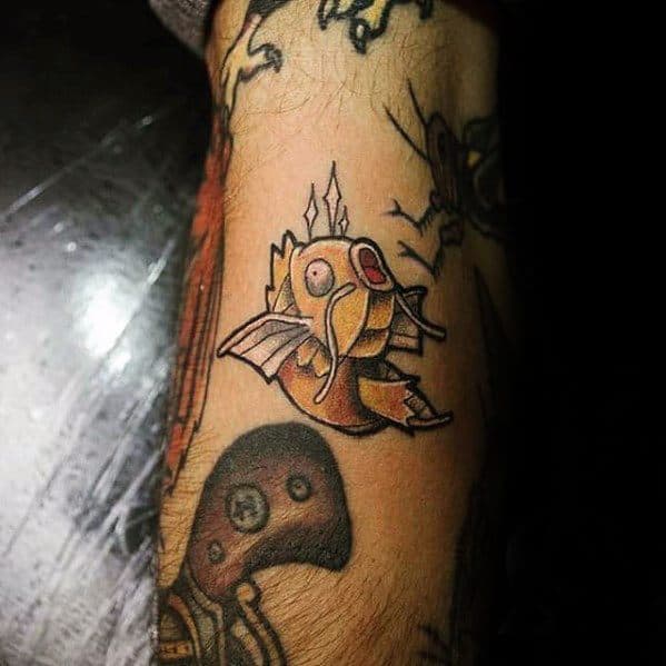 Small Magikarp tattoo with muted colors and a bold black outline, fitting seamlessly among other dark-toned ink designs.