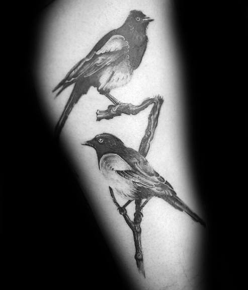 Black and gray magpie tattoo featuring two birds perched on branches, with intricate shading and fine details for a realistic and elegant look.