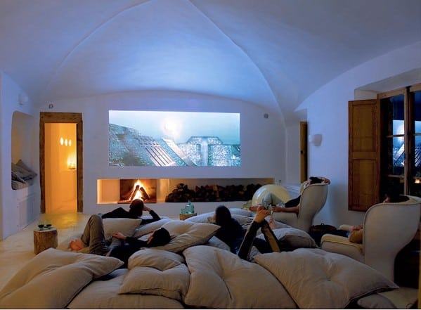 Man cave with people lounging on large cushions, watching a movie projected on the wall