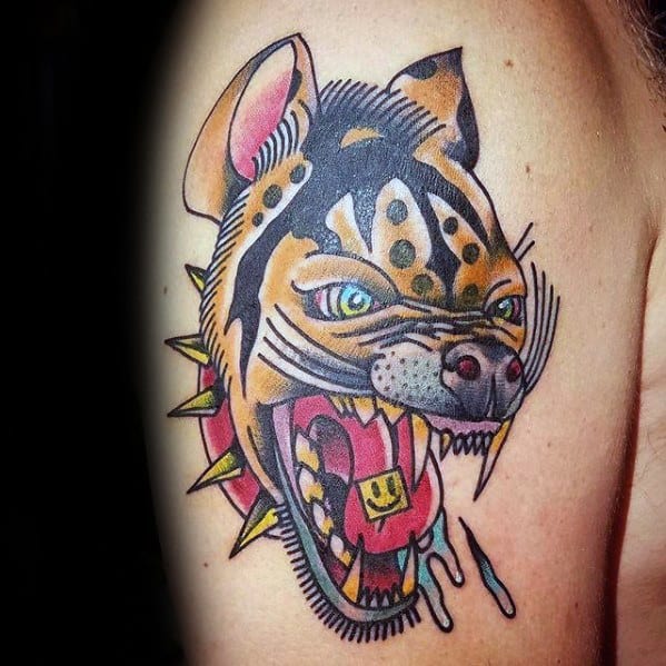 Bold neo-traditional hyena tattoo with vivid colors, green eyes, a spiked collar, and a wide snarl revealing a smiley face tongue tag.