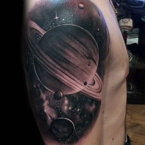 Realistic Saturn tattoo design for men on the upper arm with deep space shading, planets, stars, and nebula effects in black and grey.