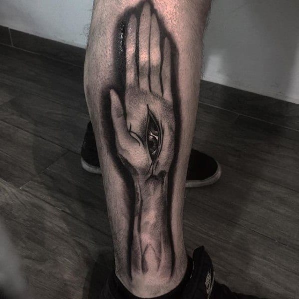 Surreal black and grey Tool-inspired leg tattoo of an elongated hand with an all-seeing eye embedded in the palm, casting deep shadows.