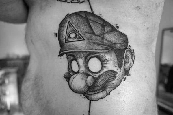 Dark surreal *Super Mario* tattoo featuring an eerie, hollow-eyed Mario with an Illuminati symbol on his cap, blending gaming with occult-inspired art.