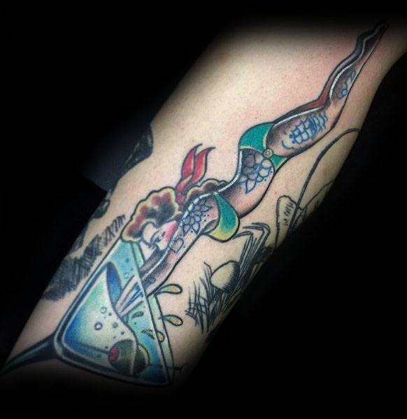 Creative martini glass tattoo featuring a mermaid diving into the drink. A bold and playful design with vibrant colors and dynamic movement.