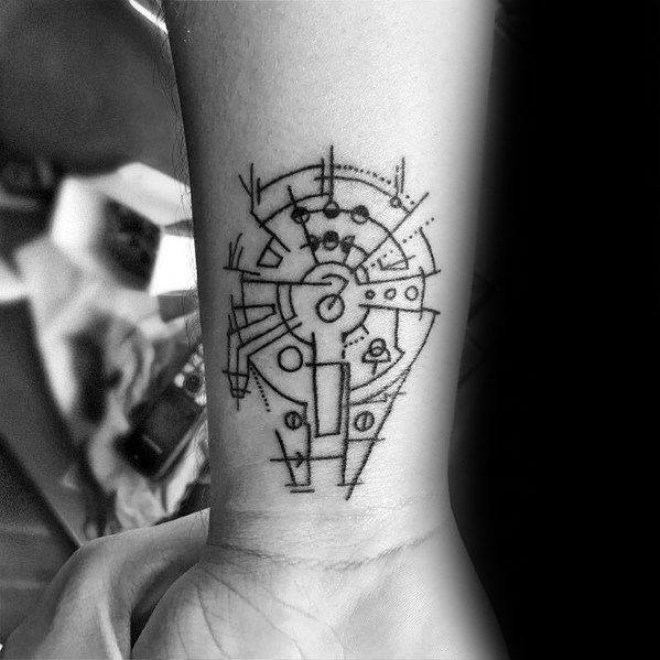 Minimalist Millennium Falcon tattoo with abstract geometric lines and shapes, placed on the inner wrist.