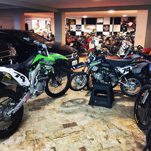 A motocross dream garage with Kawasaki bikes and vehicles in a checkerboard setting.
