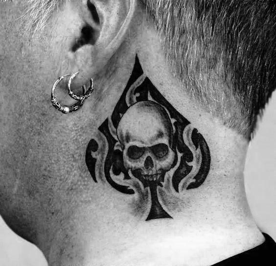 Skull tattoo on the neck inside a spade symbol with tribal flame accents, combining bold black ink and sharp detailing.
