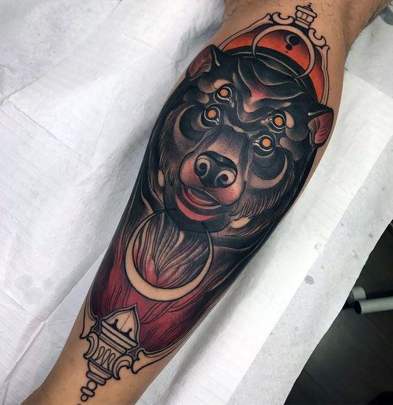 Neo-traditional bear tattoo on the leg featuring a mystical bear with extra eyes, bold shading, a yin-yang symbol, and ornamental details.