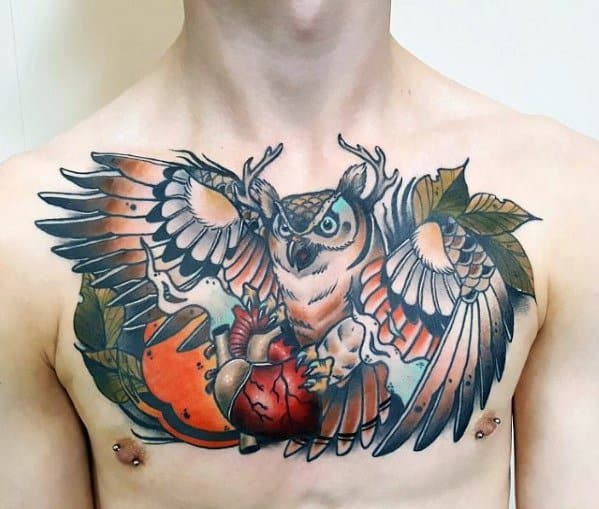 Neo-traditional owl chest tattoo with outstretched wings, antlers, bold shading, and an anatomical heart, blending nature and symbolism.