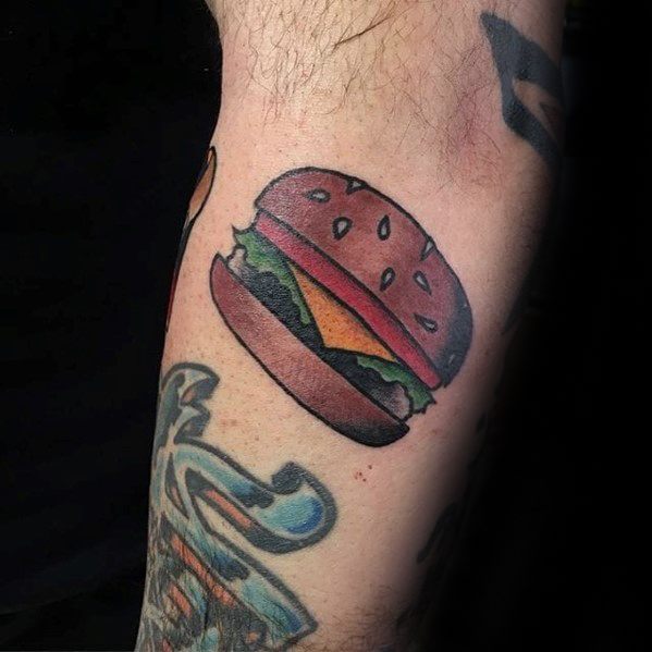 Cheeseburger tattoo with vibrant lettuce and cheese inked on a person's arm