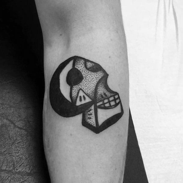 Minimalist tattoo of a Picasso-style skull with bold lines and dotwork shading, blending abstract and geometric elements.