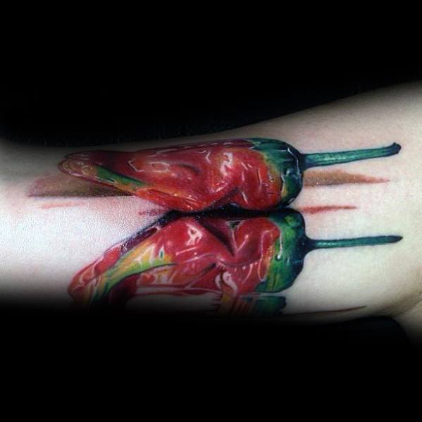 Hyper-realistic chili pepper tattoo with rich red and green shading, featuring a reflective texture for a bold and lifelike design.