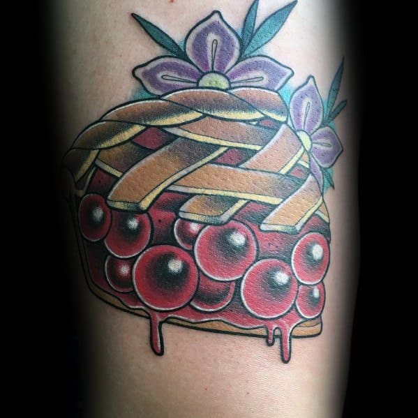 Traditional cherry pie tattoo with a lattice crust, dripping filling, and floral accents, combining bold lines and vibrant colors for a classic look