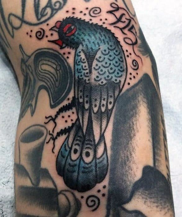 Traditional-style pigeon tattoo with bold outlines, red eyes, and swirling accents, showcasing a fierce and edgy take on classic ink.