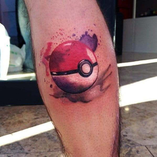 Pokeball tattoo with watercolor splashes in shades of purple, red, and black, creating a dreamy and artistic effect on the leg.