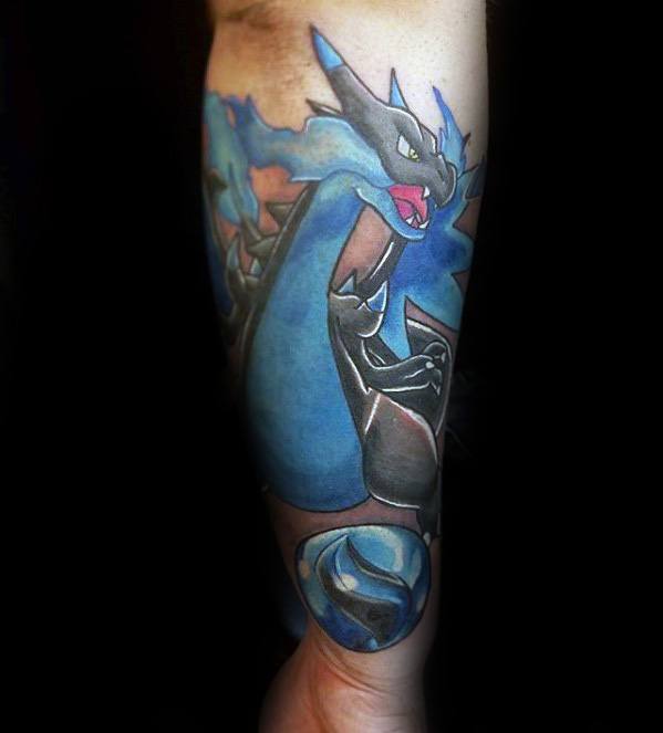 Striking Mega Charizard X tattoo on forearm with blue flames, intense shading, and a matching Poké Ball at the base.