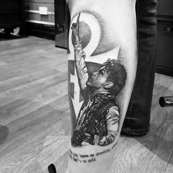 A detailed black-and-gray tattoo of Prince pointing upwards with his iconic symbol in the background