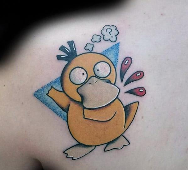 Cartoon-style Psyduck tattoo with a startled pose, expressive symbols, and blue triangle background, inked on a man's upper back.