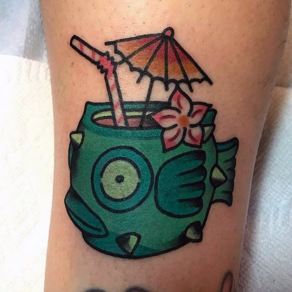 Playful pufferfish cocktail tattoo with a tropical drink, straw, umbrella, and flower, blending fun tiki bar vibes with bold colors.
