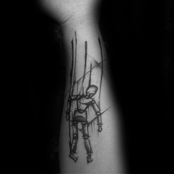 Sketch-style puppet tattoo of a marionette figure hanging by strings, giving a raw and emotional impression of control or struggle.