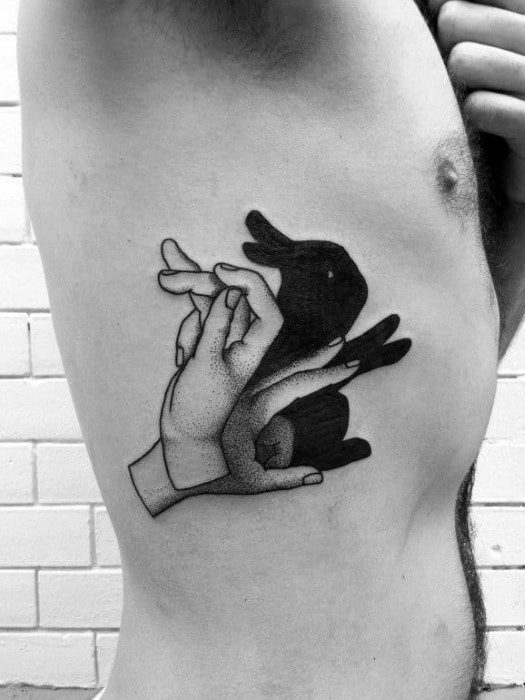 Blackwork tattoo of hands forming a playful rabbit shadow puppet, blending childhood nostalgia with minimalist design.