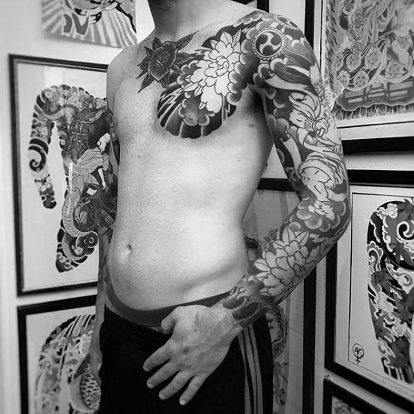 Black and grey floral Japanese-style tattoo covering the arm, shoulder, and chest with bold peony patterns and intricate shading.
