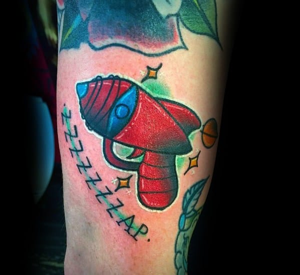 Bright and playful ray gun tattoo with a bold red and blue design, glowing accents, and the comic-style text "ZZZZZAP" for a retro sci-fi feel.