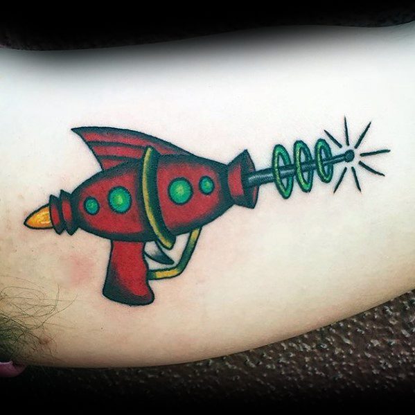 Classic retro ray gun tattoo with a bold red and green color scheme, featuring a futuristic coil barrel and a bright energy blast effect.