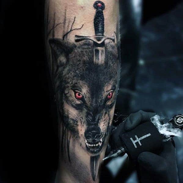 Tattoo of a wolf with red eyes and a sword above its head on an arm