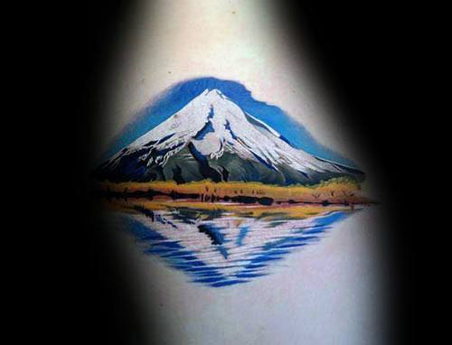 Tattoo of a snow-capped mountain reflected in a lake, creating a serene and symmetrical landscape with vibrant colors and fine details.