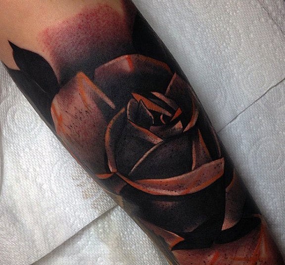 Tattoo of a black and orange rose on a forearm