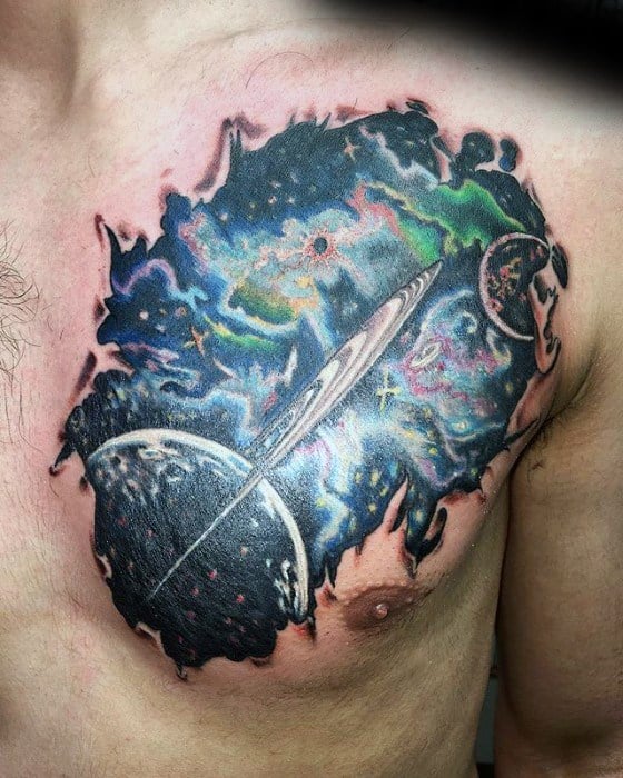Colorful Saturn tattoo design for men on the chest with cosmic nebula bursts, planets, and detailed ring patterns in a torn-skin effect.