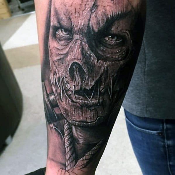 Realistic scarecrow tattoo with intense eyes, a cracked stitched mask, gas mask elements, and a thick rope around the neck.