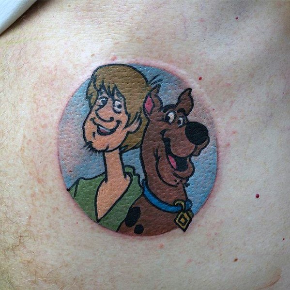 Tattoo of Shaggy and Scooby-Doo smiling inside a circular frame with a soft blue sky background.