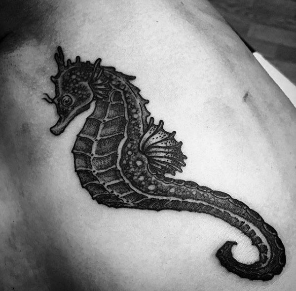 Realistic black and grey seahorse tattoo on chest, featuring intricate shading and fine details for a bold and lifelike appearance.