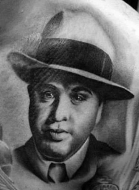 Al Capone tattoo featuring a black-and-white portrait of the gangster with his signature fedora and serious expression, capturing a classic look.