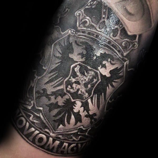 Detailed black and grey tattoo of a royal crest with a crowned shield, featuring a double-headed eagle and the word NOVIOMAGVM below.