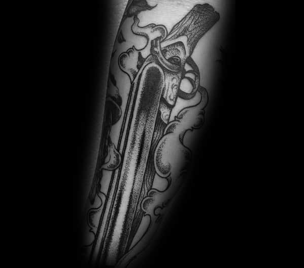 Black and grey tattoo of a double-barrel shotgun with smoke swirling around, featuring fine shading and intricate details for a bold design.