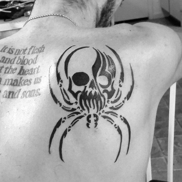 Tribal skull spider tattoo on upper back, blending a skull face with spider legs and sharp black ink lines for a bold, edgy design.