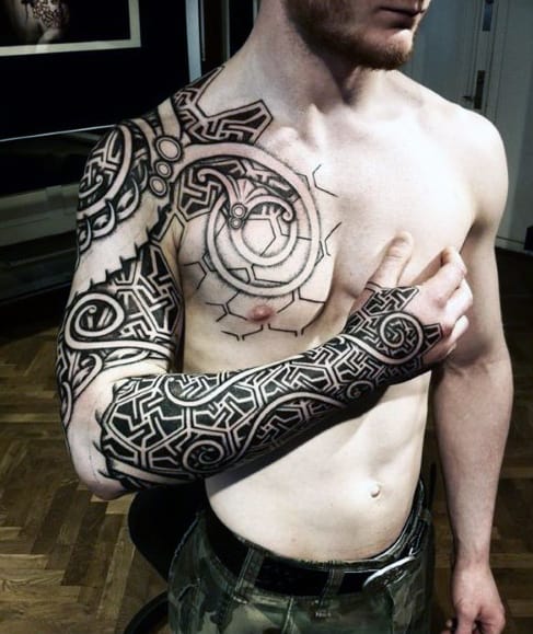 Man with intricate black tribal tattoos covering left arm and chest