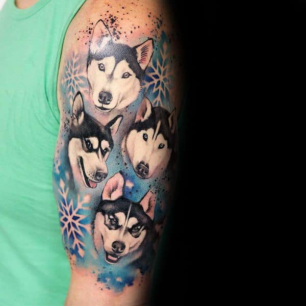 Colorful Siberian Husky tattoo sleeve on a man's arm, featuring four detailed husky portraits, blue watercolor effects, and snowflake accents.