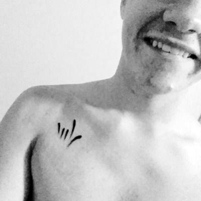 minimalist black ink tattoo of the ASL sign for "I love you," represented with simple lines on the upper chest near the shoulder