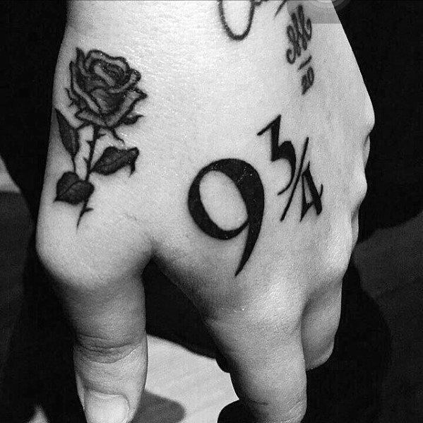 Hand with tattoos of a rose and the number 9 3/4 in black and white