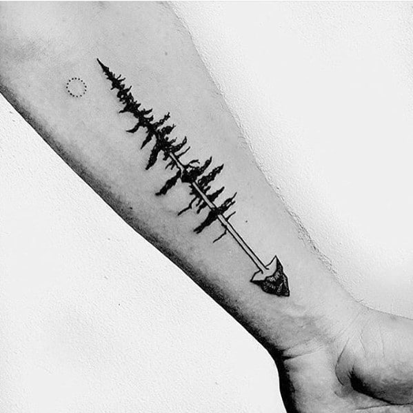 Minimalist black ink forearm tattoo of a forest forming the shaft of an arrow, symbolizing direction, strength, and a deep connection to nature.